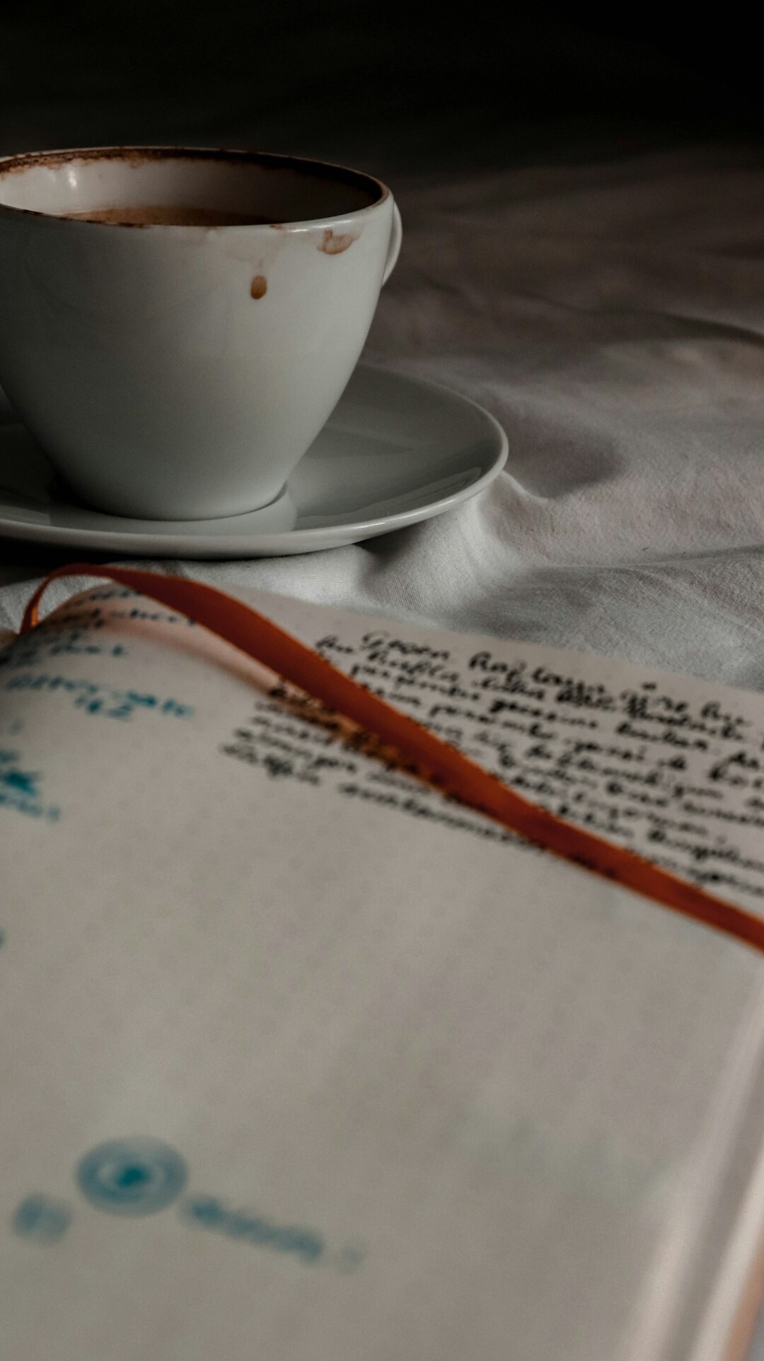 Close-up of a handwritten manuscript with a pen and coffee cup